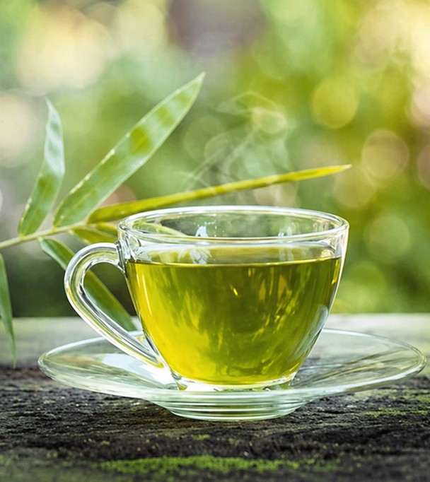 A glass cup of golden lemongrass tea with fresh stalks